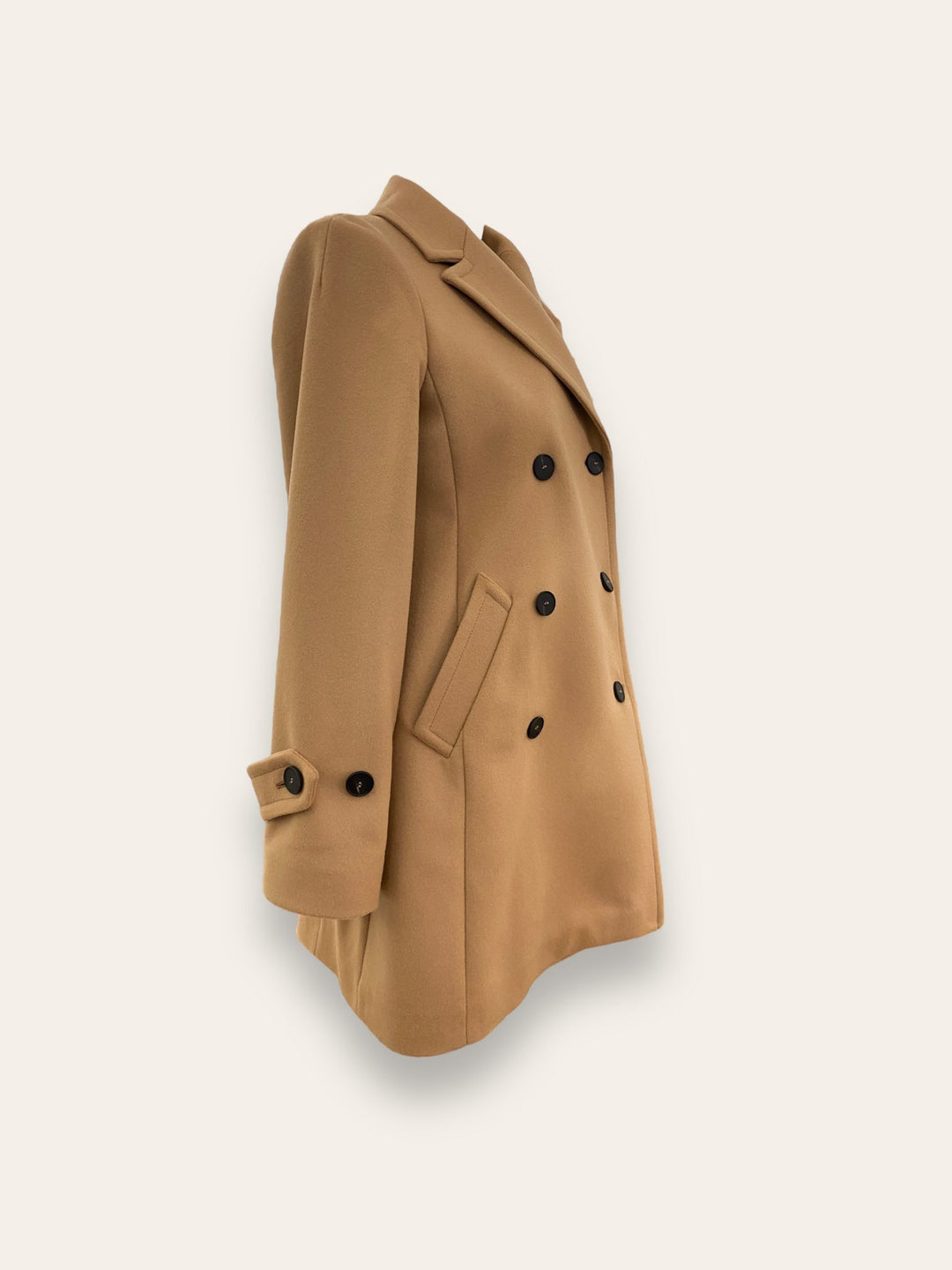 Scopri il cappotto trench Elvira color cammello di EVITA, realizzato con un pregiato mix di lana, poliammide e cashmere. Con il suo design classico e i bottoni neri, rappresenta l'artigianato italiano di alta qualità. Perfetto per un look sofisticato e senza tempo. Prodotto con passione da EVITA, made in Italy.
